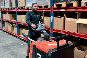 Logpart medarbetare kör en elektrisk handtruck i lagermiljö